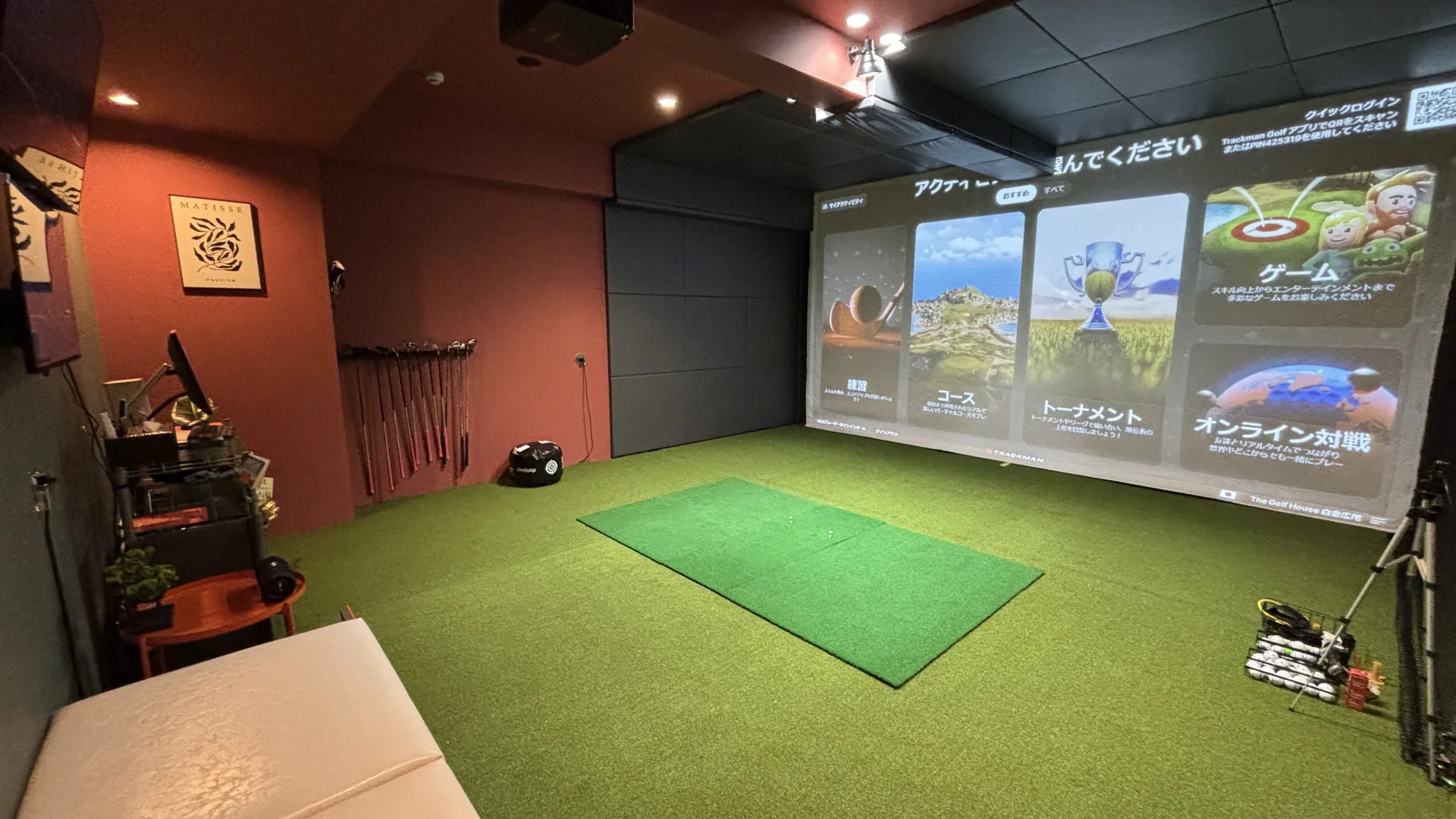 白金広尾店の完全個室の打席。赤い壁と大型スクリーンのある広い空間