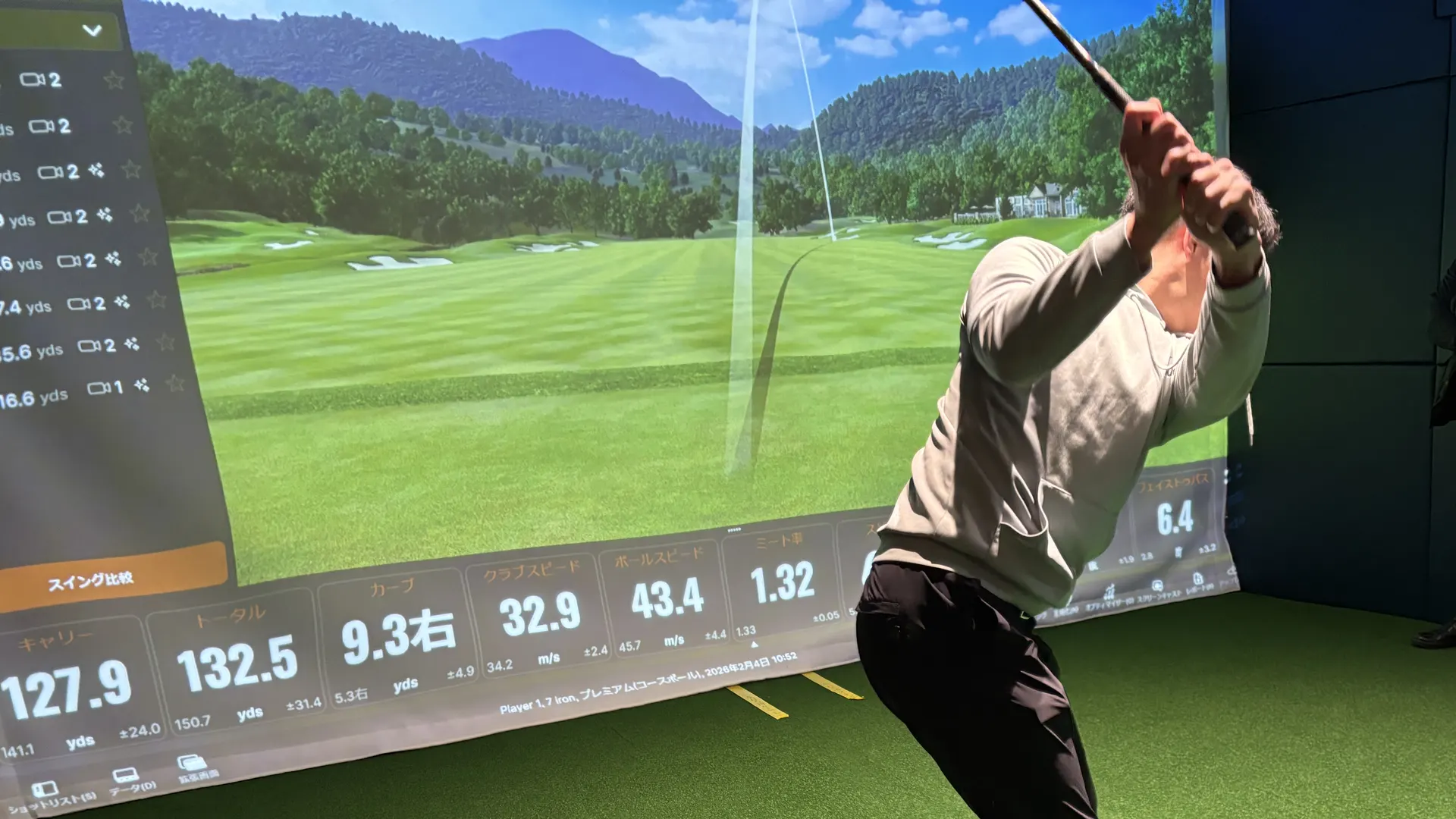 完全個室の打席でスイングする会員。大型スクリーンに映るコース